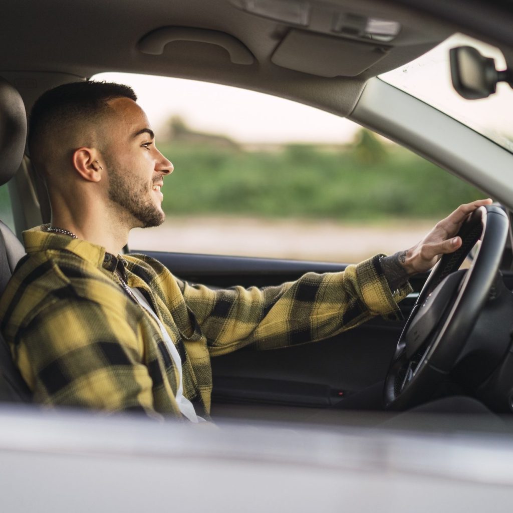 Shallow focus shot of a handsome Spanish Caucasian man sitting behind the wheel of a modern car