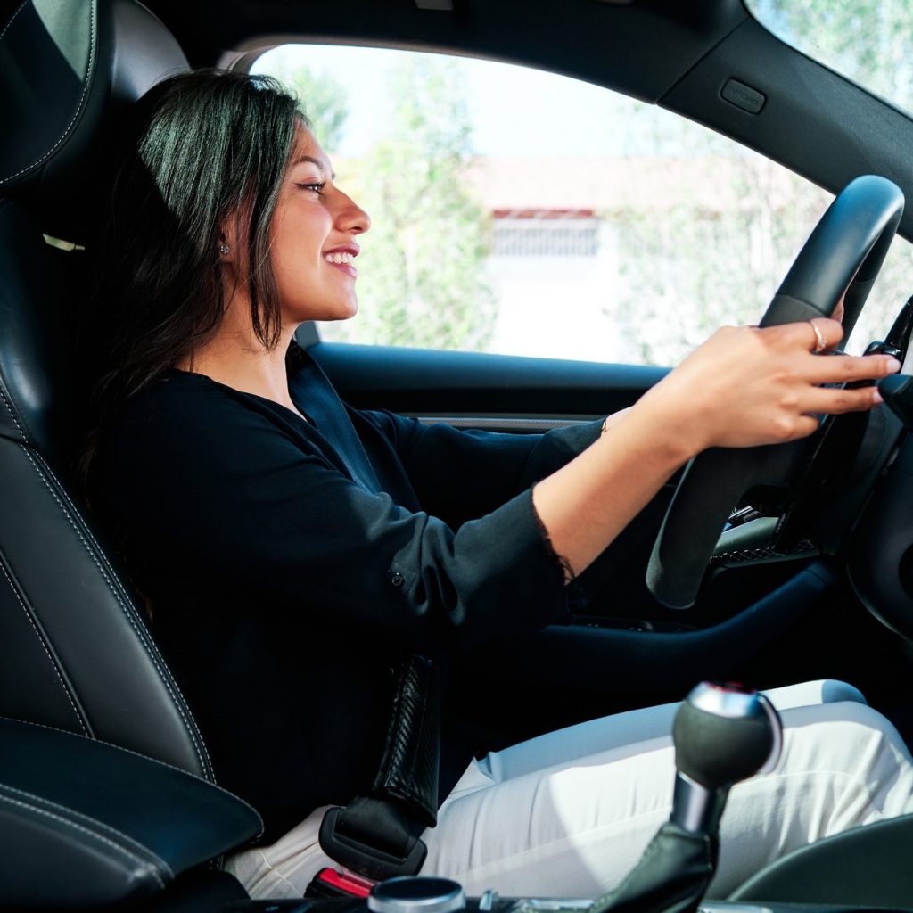 young latin woman driving luxury car